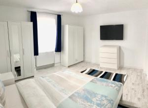 a white bedroom with a bed and a tv at Riverside Ski Apartment in Ramingstein
