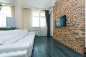 a living room with a white couch against a brick wall at 1к Люкс на Жилянская 118 in Kyiv