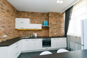 a kitchen with white cabinets and a brick wall at 1к Люкс на Жилянская 118 in Kyiv
