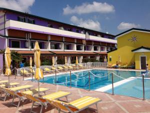 a hotel with a swimming pool and lounge chairs at Villaggio Margherita in Caorle