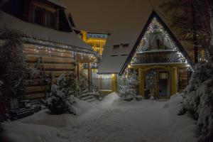 a house covered in snow with lights on it at Figusówka in Zakopane