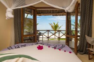 a bedroom with a bed and a window overlooking the ocean at Zanziblue in Matemwe