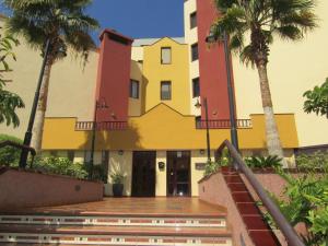 a building with palm trees in front of it at Olivia Sunset Playa in Puerto de Santiago