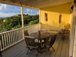 une terrasse couverte en bois avec une table et des chaises. dans l'établissement Breeze Cottage, à Five Islands Village