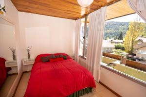 1 dormitorio con cama roja frente a una ventana en Departamento céntrico San Martín de los Andes en San Martín de los Andes