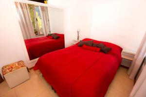 1 dormitorio con 2 camas rojas y espejo en Departamento céntrico San Martín de los Andes en San Martín de los Andes
