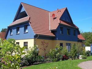 een blauw en geel huis met een rood dak bij Ferienwohnung Baumann in Prerow