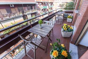 a balcony with a wooden table and chairs and flowers at Quelli della via Gluck in Rome