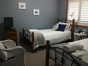 a bedroom with two beds and a tv and a chair at Kiama Guesthouse in Kiama