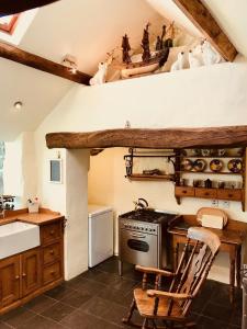a kitchen with a stove and a table and a chair at The Piggery - North Wales Retreat in Pwllheli