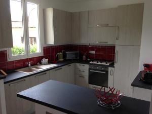 a kitchen with white cabinets and red tile at Le 43 in La Trinité