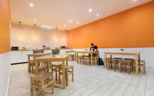 une personne assise à un comptoir dans une cuisine avec des tables dans l'établissement Best Guest Porto Hostel, à Porto