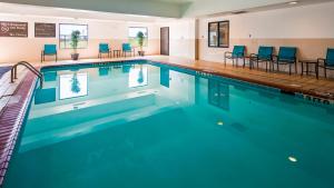 a swimming pool with blue chairs in a hotel room at Ramada by Wyndham Burkburnett - Wichita Falls in Burkburnett