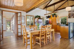 cocina y comedor con mesa de madera y sillas en Mandala Bruny Island, en Alonnah