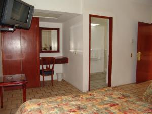 ein Schlafzimmer mit Bett, Schreibtisch und Fernseher in der Unterkunft Hotel Posada Arcos in San Juan de los Lagos