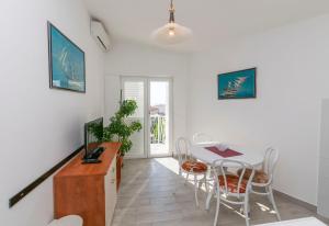 een eetkamer met een tafel en stoelen en een televisie bij Apartment Nensi in Primošten