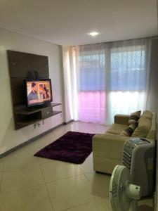 Residente Lord Cabo Frio في كابو فريو: غرفة معيشة مع أريكة وتلفزيون بشاشة مسطحة
