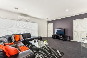 a living room with a black leather couch and a flat screen tv at Urban Corporate Apartment in Mount Gambier