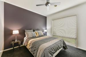 a bedroom with a bed and a window with a ceiling fan at Urban Corporate Apartment in Mount Gambier