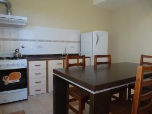 a kitchen with a black table and a white refrigerator at Apart Hotel Vista San Lucas in Carpintería