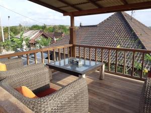 a balcony with a table and chairs on a deck at Kakiang Homestay in Nusa Lembongan