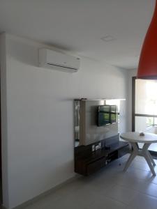 a white living room with a table and a tv at Carneiros Beach Resort in Tamandaré