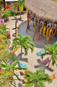 a playground with palm trees and chairs in the sand at Tribu Hostel in Holbox Island