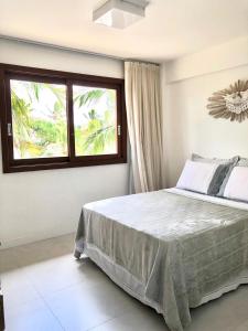 ein Schlafzimmer mit einem großen Bett und einem Fenster in der Unterkunft Residencial Enseada Praia do Forte Apto 130 in Praia do Forte