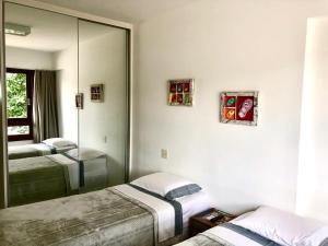 a bedroom with two beds and a mirror at Residencial Enseada Praia do Forte Apto 130 in Praia do Forte