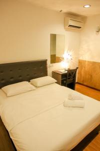 a large white bed in a room with a desk at N K Hotel in Muar