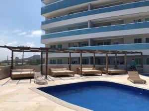 Un hotel con piscina y sillas y un edificio. en Le Bon Vivant 307 B, en Arraial do Cabo
