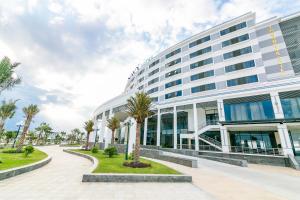 a large building with palm trees in front of it at Navy Hotel Cam Ranh in Cam Ranh
