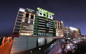 a tall building with green windows at night at PALM PARK Hotel Surabaya in Surabaya