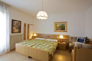 sypialnia z dużym łóżkiem i żyrandolem w obiekcie Albergo Bellaria w mieście Carano
