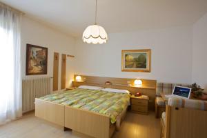 a bedroom with a large bed and a chandelier at Albergo Bellaria in Carano