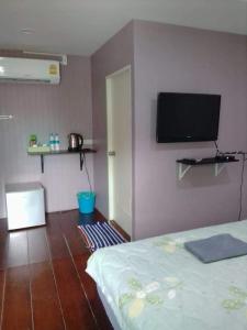 a bedroom with a bed and a flat screen tv at รุ่งฟ้า ฟาร์มสเตย์ in Ban Sap Phrik