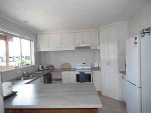 a kitchen with white cabinets and a white refrigerator at 46 MacKenzie in Twizel