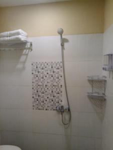 y baño con ducha y pared de azulejos. en Muara Inn ternate en Ternate