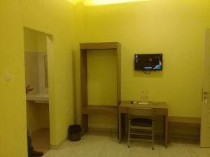 Cette chambre dispose d'une table et d'une télévision sur un mur jaune. dans l'établissement Muara Inn ternate, à Ternate