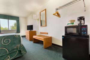 Habitación con cama, TV y mesa. en Travelodge by Wyndham Sharon Springs, en Sharon Springs