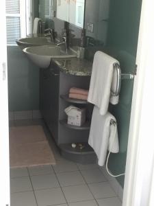 a bathroom with a sink and a mirror and towels at Oneroa Bay Villas in Oneroa +29 photos