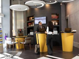 a man and a woman standing at a counter with laptops at Mercure Sao Paulo Bela Vista in Sao Paulo