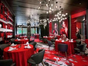 a restaurant with red tables and chairs and chandeliers at Pullman Kuala Lumpur City Centre Hotel & Residences in Kuala Lumpur +102 photos