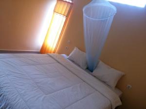 1 dormitorio con 1 cama blanca grande y ventana en Antoneri Lodge, en Kelimutu
