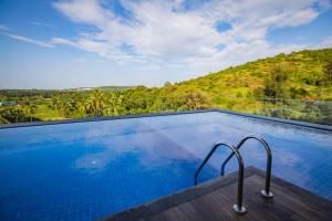 a swimming pool with a view of a hill at Nanu Resort, Arambol in Arambol