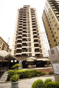 a tall building with tables and umbrellas in front of it at London Class Hotéis in Sao Paulo