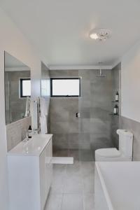 a white bathroom with a toilet and a sink at By Moonlight in Wattle Hill