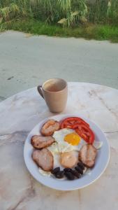 een bord eieren en worst en een kop koffie bij Andy's Gardens in Gerani Chanion
