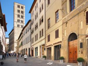 un grupo de personas caminando por una calle con edificios en Il Canzoniere, en Arezzo