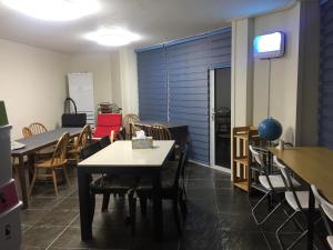 a dining room with tables and chairs and a tv at Jeju Guesthouse in Jeju